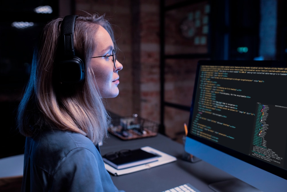 Especialista en ingeniería de datos trabajando en análisis y programación frente a monitor con código.