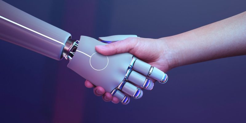 Mano humana estrechando la mano robótica en representación del asesoramiento en inteligencia artificial.