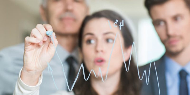 Equipo de consultores definiendo estrategia empresarial con proyecciones de rendimiento en gráficos.