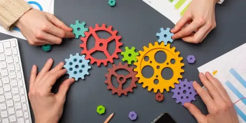 Equipo trabajando en la optimización de procesos de negocio y producción representados con engranajes de colores.